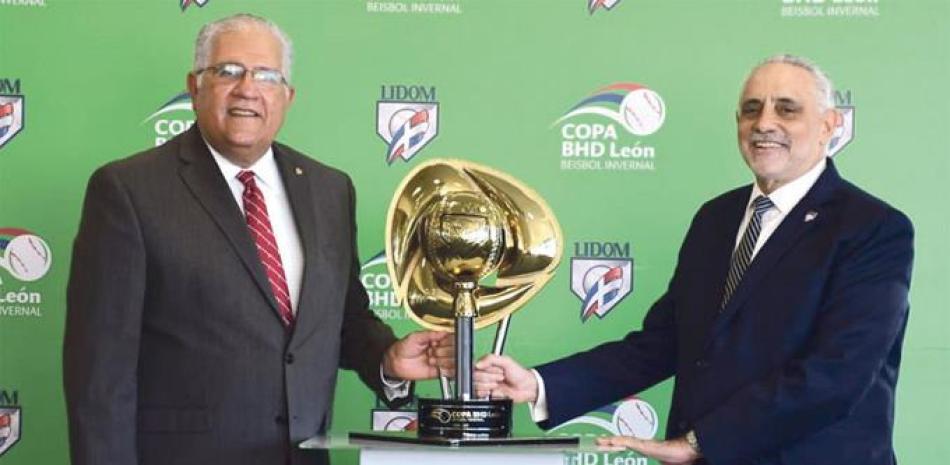 Luis Lembert, Vicepresidente ejecutivo de Banca del BHD León y Vitelio Mejía presidente de Lidom muestran la copa que se llevará el equipo campeón.