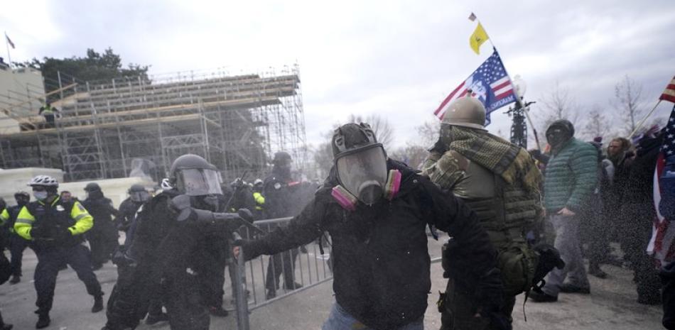 Seguidores del presidente de Estados Unidos, Donald Trump, tratan de desmontar una barrera policial, el 6 de enero de 2021, en el Capitolio, en Washington.

Foto: AP/Julio Cortez
