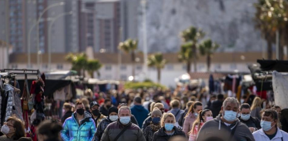 En esta imagen de archivo, tomada el 4 de enero de 2021, gente con mascarilla pasea entre los puestos de un mercadillo semanal en la ciudad española de La Línea. (AP Foto/Emilio Morenatti, archivo)
