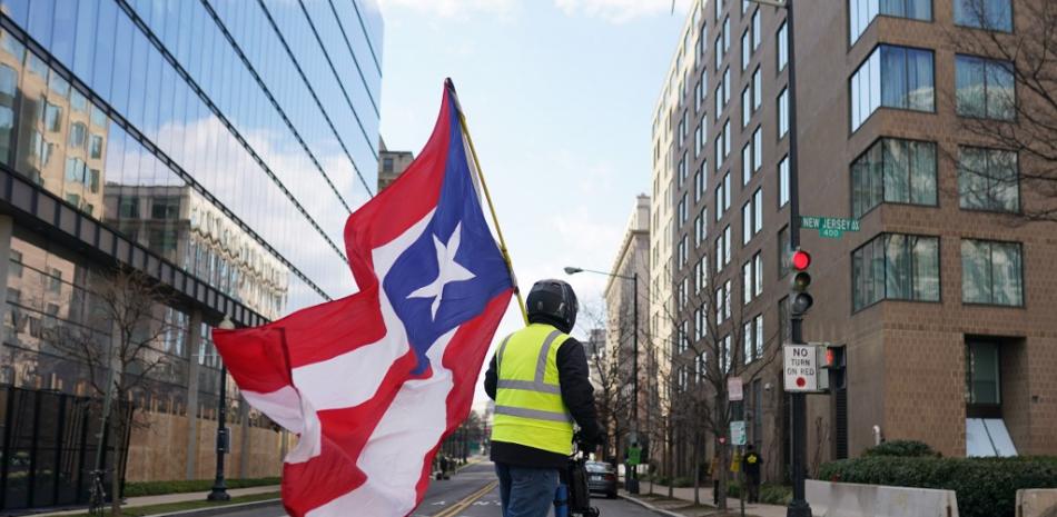 Un hombre que ondea la bandera de Puerto Rico conduce una motoneta por la Avenida New Jersey luego de la investidura del presidente Joe Biden el 20 de enero de 2021 en Washington, DC. Nathan Howard / Getty Images / AFP