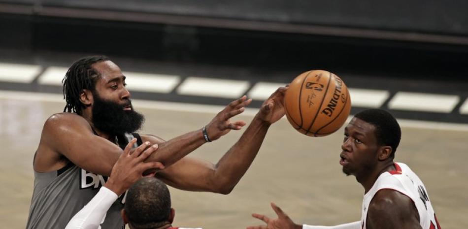 El escolta de los Brooklyn Nets, James Harden, a la izquierda, pasa el balón entre el alero de los Miami Heat, Andre Iguodala (28), y el escolta Kendrick Nunn, durante la segunda mitad de un juego de baloncesto de la NBA este lunes.