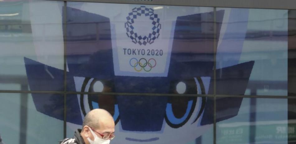 Un hombre camina frente a una pantalla donde se publicitan los Juegos Olímpicos en Tokio, este miércoles 27 de enero de 2021
