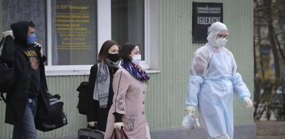 Una trabajadora sanitaria con un traje de protección acompaña a estudiantes hasta una ambulancia, en Minsk, Bielorrusia, el 21 de abril de 2020.

Foto: AP/ Sergei Grits