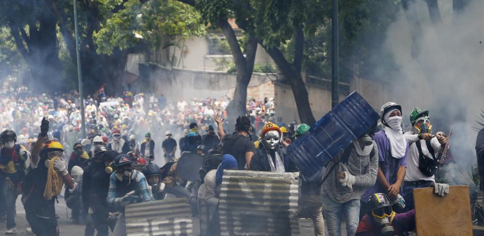 Manifestantes enmascarados y con cascos se enfrentan a las fuerzas de seguridad durante una marcha de la oposición del Primero de Mayo en Caracas, Venezuela, el lunes 1 de mayo de 2017.

Foto: AP / Ariana Cubillos