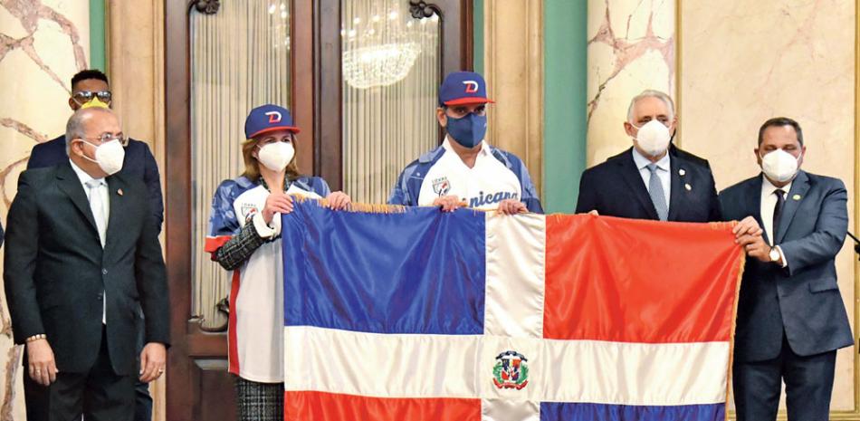 El presidente Luis Abinader, en compañía de la vicepresidenta Raquel Peña, hace entrega de la bandera dominicana a Vitelio Mejía, titular de Lidom. Figuran, asimismo, el ministro de Salud Pública, Plutarco Arias, y Junior Noboa, Comisionado de Béisbol.