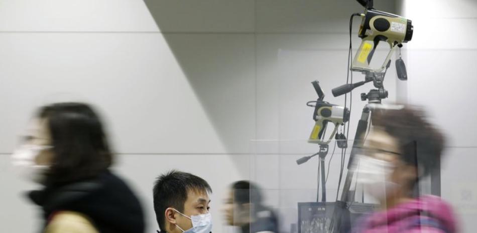 Pasajeros con máscaras pasan mientras un oficial de cuarentena, en el centro, monitorea una termografía durante una inspección de cuarentena en el aeropuerto internacional de Kansai en Osaka, Japón occidental, el miércoles 22 de enero de 2020.

Foto: Kota Endo/ AP