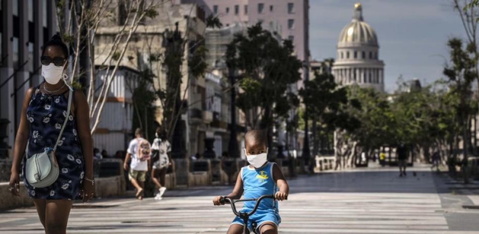 Una mujer acompaña a un niño en bicicleta, ambos con mascarillas protectoras como medida de precaución en medio de la propagación del nuevo coronavirus, en La Habana, Cuba, el viernes 3 de julio de 2020.

Foto: AP/ Ramon Espinosa
