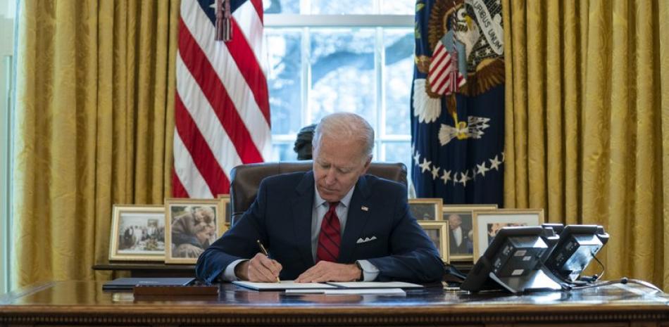 Fotografía de archivo del 28 de enero de 2021 del presidente Joe Biden firmando una serie de órdenes ejecutivas sobre atención médica, en la oficina Oval de la Casa Blanca en Washington. (AP Foto/Evan Vucci, Archivo)