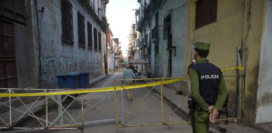 Un policía controla el acceso dentro y fuera de un área acordonada para presentar casos de COVID-19, en La Habana el 2 de febrero de 2021. 

Yamil LAGE / AFP