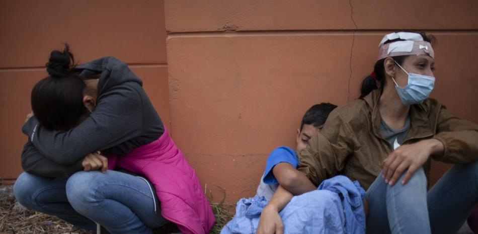 ARCHIVO - En esta imagen del 17 de enero de 2021, mujeres de una caravana de migrantes hondureños que resultaron heridas cuando intentaban llegar a la frontera estadounidense lloran junto a una autopista tras chocar con policías y soldados guatemaltecos en Vado Hondo, Guatemala. (AP Foto/Sandra Sebastian, Archivo)