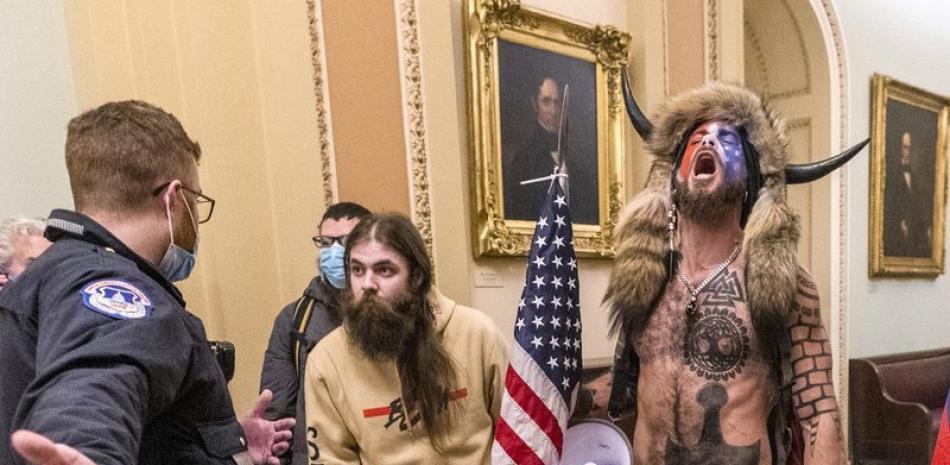 A la derecha, con la cara pintada, un casco con cuernos y sin camisa, se ve a Jacob Chansley durante el asalto al Capitolio en Washington el 6 de enero del 2021. Foto: AP/Manuel Balce Ceneta.