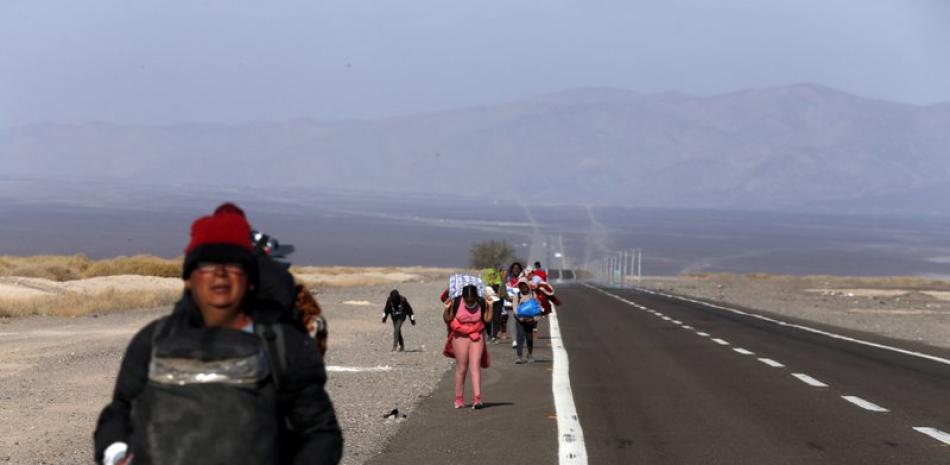 Migrantes, la mayoría de Venezuela, caminan junto a la carretera después de cruzar a Chile desde la frontera con Bolivia cerca de Colchane, Chile, el sábado 6 de febrero de 2021. (AP Foto/Luis Hidalgo