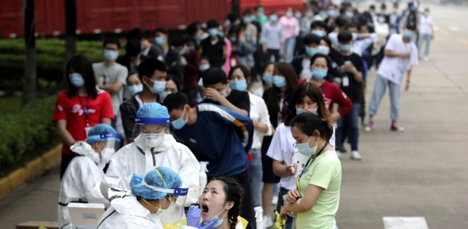 En esta foto de archivo del 15 de mayo de 2020, las personas hacen fila para que los trabajadores médicos tomen hisopos para la prueba del coronavirus en una gran fábrica en Wuhan, en la provincia de Hubei, en el centro de China.

Foto: Chinatopix/AP