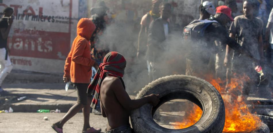 Un manifestante levanta una barricada en llamas durante una protesta para exigir la renuncia del presidente haitiano Jovenel Moise en Port-au-Prince, Haití, el domingo 7 de febrero de 2021.

Foto: AP/ Dieu Nalio Chery