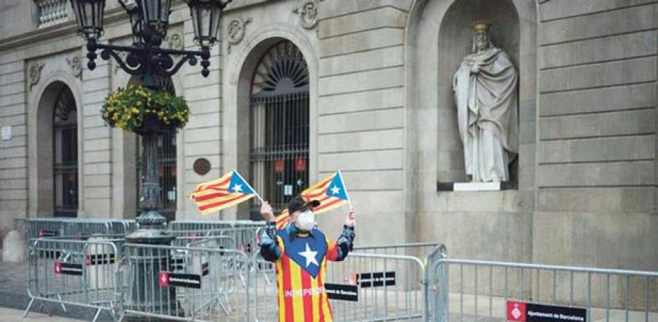 Josep Maria Valve, de 81 años, ondea banderas independentistas catalanas, ante el ayuntamiento de Barcelona, el domingo 31 de enero de 2021. AP