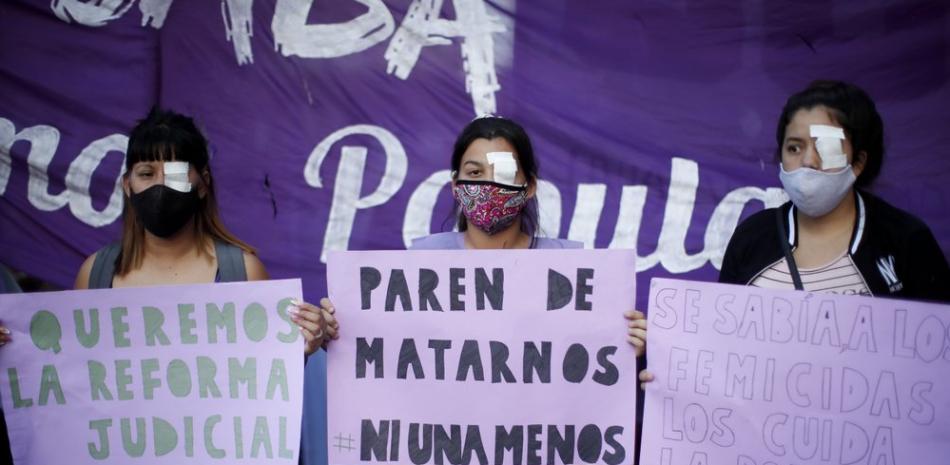 Mujeres con uno de los ojos tapados sostienen carteles durante una protesta contra la violencia de género, en Buenos Aires, Argentina, el miércoles 17 de febrero de 2021. (AP Foto/Natacha Pisarenko)