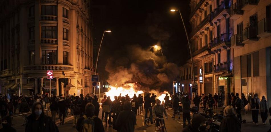 Gente reunida junto a una barricada en llamas durante las protestas por el encarcelamiento del rapero Pablo Hasél en Barcelona, España. (AP Foto/Felipe Dana)