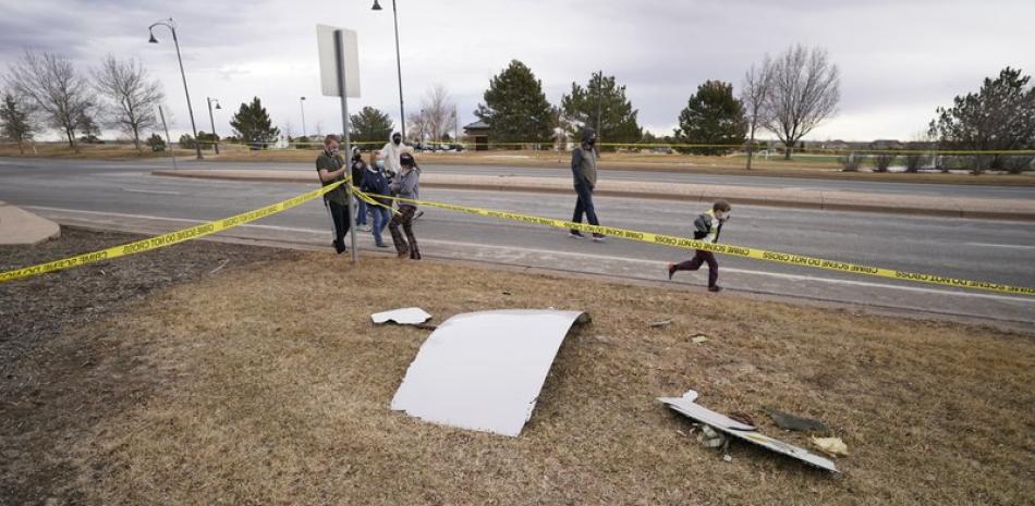 Varias personas echan un vistazo a partes de un avión de pasajeros que se desprendieron y cayeron sobre un vecindario en Broomfield, Colorado.