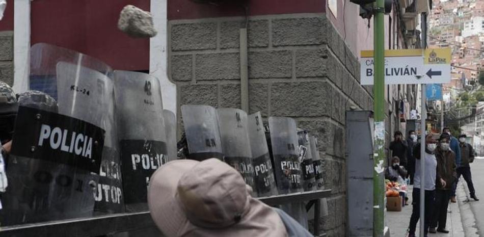Un hombre lanza una piedra a la policía frente al palacio de gobierno durante una protesta en apoyo a los trabajadores de la salud en medio de la pandemia de COVID-19 en La Paz, Bolivia, el lunes 22 de febrero de 2021. Los trabajadores de la salud han convocado una huelga general para protestar contra una nueva ley sanitaria de emergencia que, entre otras cosas, permite la contratación de médicos extranjeros. (AP Foto/Juan Karita)