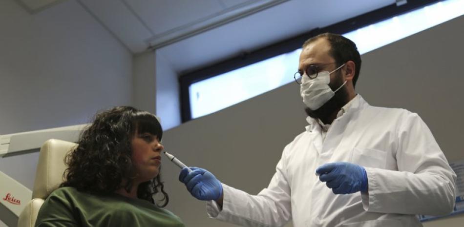 La Dra. Clair Vandersteen, lanza un tubo de olores debajo de la nariz de una paciente, Gabriella Forgione, durante las pruebas en un hospital en Niza, en el sur de Francia, para ayudar a determinar por qué no ha retornado su olfato o sabor desde que contrajo COVID-19 en noviembre de 2020. (Foto AP / John Leicester)