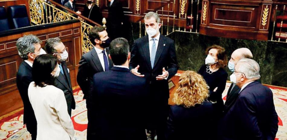El rey Felipe de España (centro) conversa con políticos, incluido el presidente de gobierno Pedro Sánchez (de espaldas a la cámara), dentro del Parlamento español, el martes 23 de febrero de 2021, en Madrid. AP