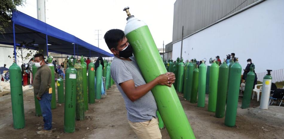 Un hombre carga una botella vacía de oxígeno para rellenarla tras hacer fila en la Villa El Salvador de Lima, el jueves 18 de febrero de 2021. 

Foto: AP/ Martin Mejia