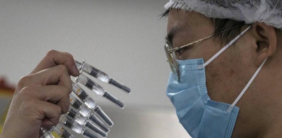En esta foto de archivo del 24 de septiembre de 2020, un trabajador inspecciona jeringas para la vacuna contra el COVID-19 producida por Sinovac en su planta en Beijing, China. (AP Foto/Ng Han Guan, File)