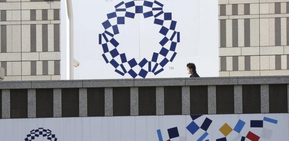 Un hombre con mascarilla camina frente al logotipo de los Juegos Olímpicos de Tokio. (AP Foto/Koji Sasahara)