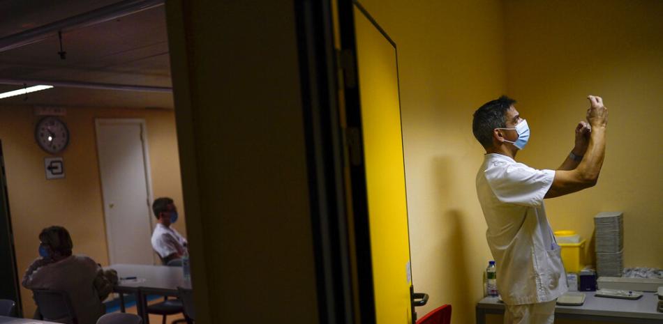 Un enfermero prepara una jeringa con la vacuna de Pfizer/Biontech contra el COVID-19 junto a empleados de salud descansando después de ser vacunados en el hospital CHR Citadelle en Lieja, el jueves 11 de febrero de 2021.

Foto: AP/Francisco Seco