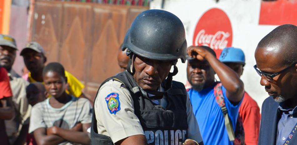 Un policía observa los cadáveres de dos hombres que permanecen en medio de la calle afuera de la cárcel de Croix-des-Bouquets tras una fuga de presos hoy, cerca de Puerto Príncipe (Haití).