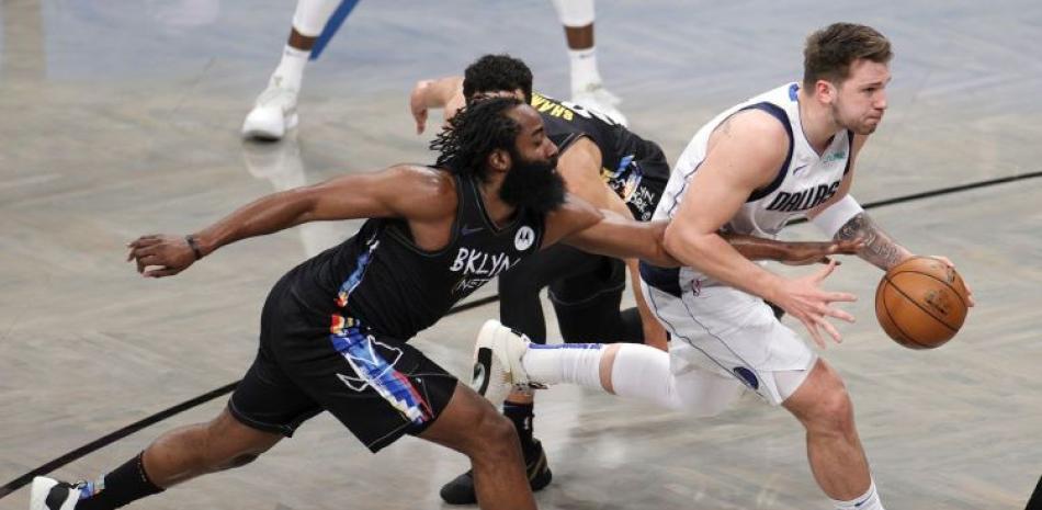 Luka Doncic, de los Mavericks, maneja el balón ante la presión defensiva de James Harden, de los Nets, en acción del sábado por la noche de la NBA.