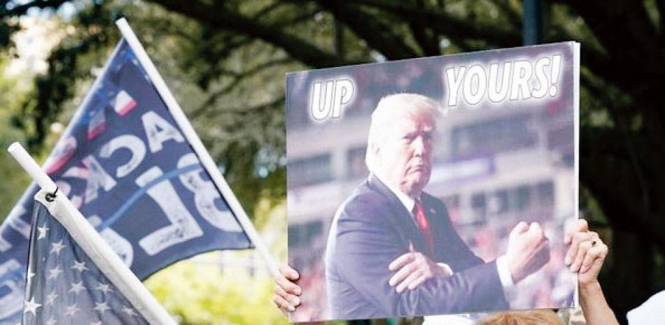 Seguidores de Donald Trump ondean banderas a los conductores que pasan frente al centro de convenciones en la Conferencia de Acción Política Conservadora el sábado 27 de febrero de 2021 en Orlando, Florida. AP