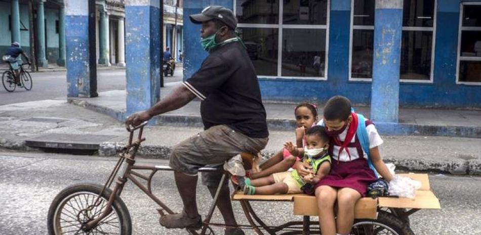 Un hombre transporta niños en su triciclo, en La Habana, Cuba, el viernes 8 de enero de 2021, en medio de la nueva
pandemia de coronavirus. AP