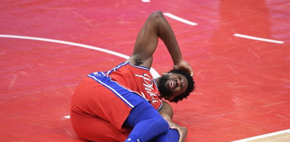 El pívot de los 76ers de Filadelfia, Joel Embiid, reacciona luego de caer mal durante la segunda mitad del partido de la NBA contra los Wizards de Washington. (AP)