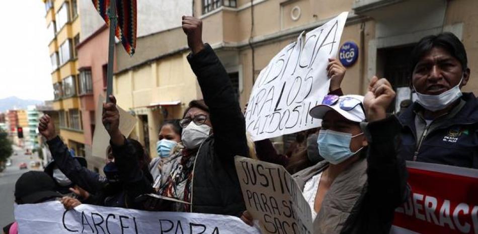 Una mujer sostiene una pancarta mientras la gente protesta contra la ex presidenta interina de Bolivia, Jeanine Áñez, frente a la estación de policía donde está detenida en La Paz, Bolivia, el domingo 14 de marzo de 2021. (Foto AP/Juan Karita)