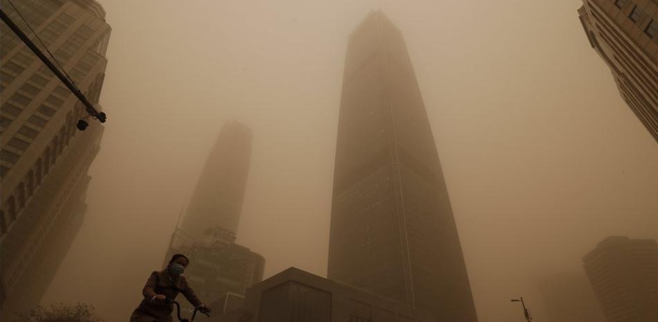 Un ciclista y varios conductores pasan entre edificios de oficinas en medio de una tormenta de arena, durante la hora punta en el distrito financiero de Beijing, el lunes 15 de marzo de 2021. 

 

(AP Foto/Andy Wong)