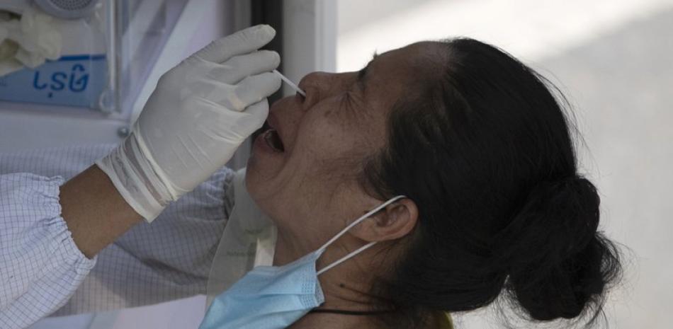 Un trabajador sanitario toma una muestra a una mujer para una prueba de detección del coronavirus, en Bangkok, Tailandia, el 15 de marzo de 2021. (AP Foto/Sakchai Lalit)