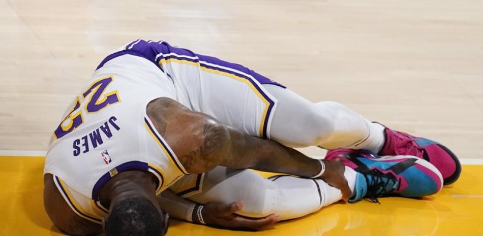El alero de los Lakers de Los Ángeles LeBron James se toca el tobillo tras sufrir una lesión en el encuentro ante los Hawks de Atlanta el sábado 20 de marzo del 2021.