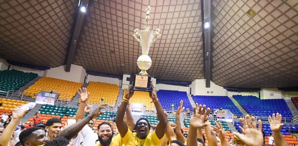 Felipe López, presidente del club Gregorio Urbano Gilbert, eleva la copa que acredita a esa institución como campeón del torneo de baloncesto superior de Santiago 2020.