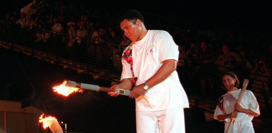 1996 - La leyenda del boxeo Muhammed Ali enciende la llama olímpica, mientras la nadadora estadounidense Janet Evans observa durante la ceremonia de apertura de los Juegos Olímpicos de verano de 1996 en Atlanta, el 19 de julio de 1996 (AP Photo / Michael Probst).