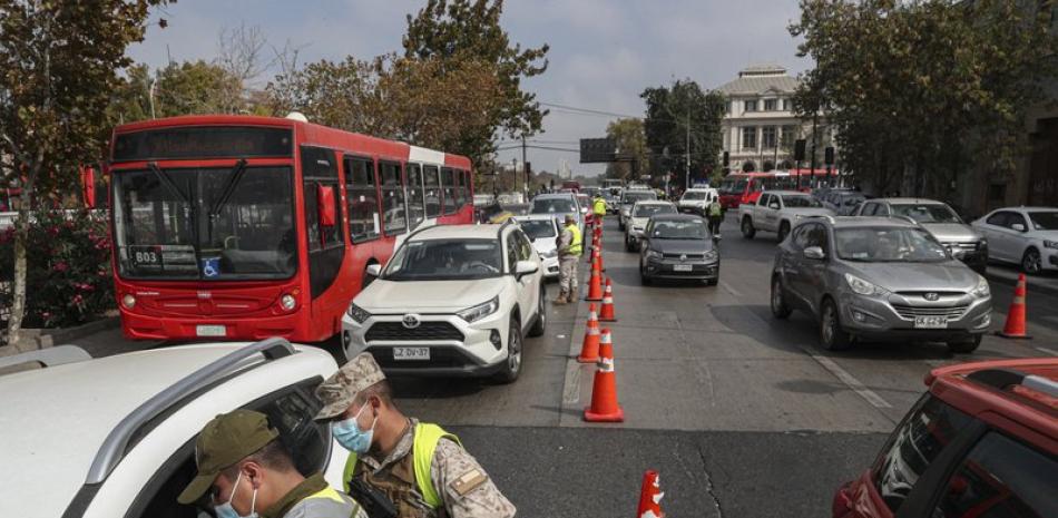 Soldados verifican los permisos de tránsito de los viajeros en un puesto de control en Santiago de Chile. Foto: AP/Esteban Félix.