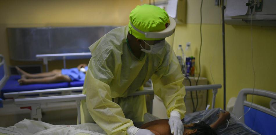 Un trabajador de salud da palmadas en la espalda a un paciente con COVID-19 el sábado 27 de marzo de 2021 en la unidad de cuidados intensivos del hospital público Ana Francisca Pérez de León II, en Caracas, Venezuela.

Foto: AP/Matías Delacroix