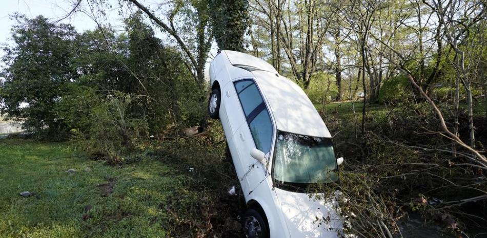 Un automóvil que fue arrastrado por las inundaciones se apoya contra un árbol en un arroyo el domingo 28 de marzo de 2021, en Nashville, Tennessee. Fuertes lluvias en Tennessee inundaron casas y carreteras cuando una línea de tormentas severas cruzó el estado. (Foto AP / Mark Humphrey)