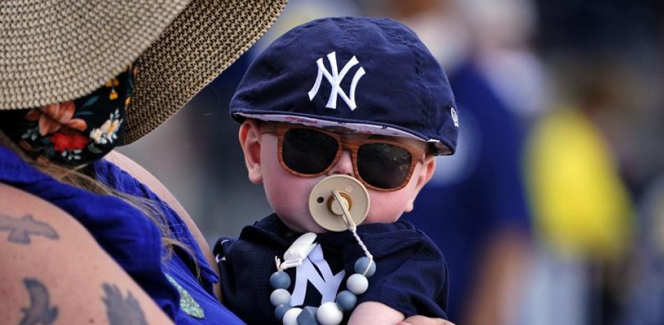 El fanático de los Yankees de Nueva York, Britt Hamlin, de seis meses de edad, es sostenido por su madre Casey Hamlin, de Long Beach Island, Nueva Jersey, durante un juego de béisbol de exhibición de entrenamiento de primavera entre los Filis de Filadelfia y los Yankees de Nueva York en Tampa, Florida. (AP Photo / Gene J. Puskar)