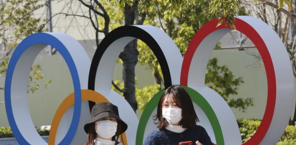 En esta foto de archivo del 17 de marzo de 2021, gente pasa frente a los anillos olímpicos en Tokio.
