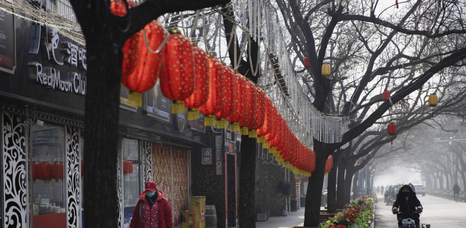En esta foto tomada el martes 11 de febrero de 2020, una mujer pasa junto a la decoración del Año Nuevo Lunar y los bares cerrados en un distrito comercial en Beijing, China.

Foto: AP / Ng Han Guan