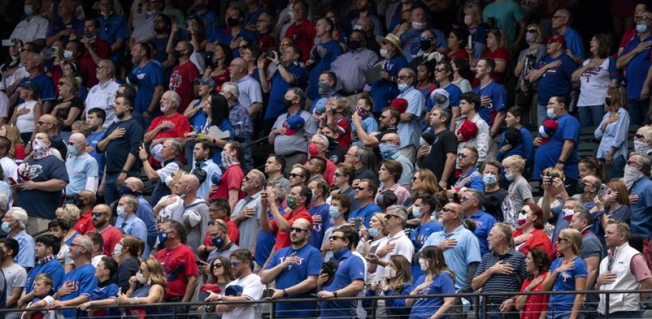 Aficionados de pie para el himno nacional antes del partido entre los Rangers de Texas y los Azulejos de Toronto, este lunes, en Arlington, Texas.