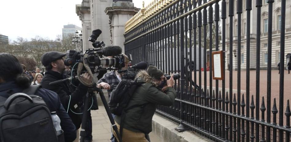 Fotografía del viernes 9 de abril de 2021, de miembros de los medios de comunicación tomando imágenes de un anuncio sobre la muerte del príncipe Felipe de Gran Bretaña, exhibido en la cerca del Palacio de Buckingham en Londres. (AP Foto/Matt Dunham).