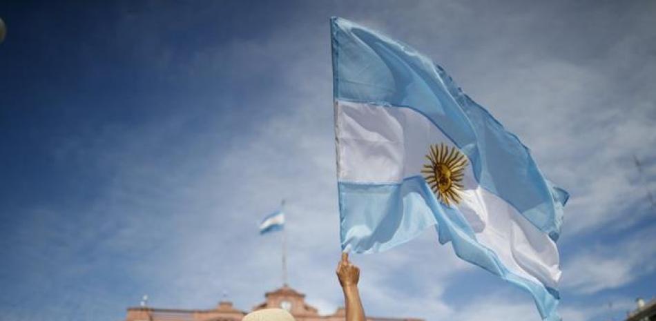 Una manifestante ondea una bandera de Argentina delante de la Casa Rosada durante una protesta contra el presidente del país, Alberto Fernández, y su gestión de las vacunas contra el COVID-19, en Buenos Aires, Argentina, el 27 de febrero de 2021. (AP Foto/Natacha Pisarenko)