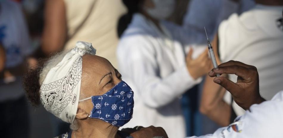 Un trabajador médico se dispone a vacunar contra el coronavirus a una mujer en Duque de Caxias, Brasil, el 24 de marzo de 2021. (AP Foto/Silvia Izquierdo, File)